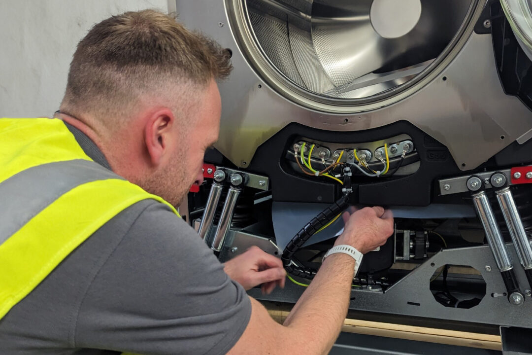 An engineer fixing a commercial laundry machine.